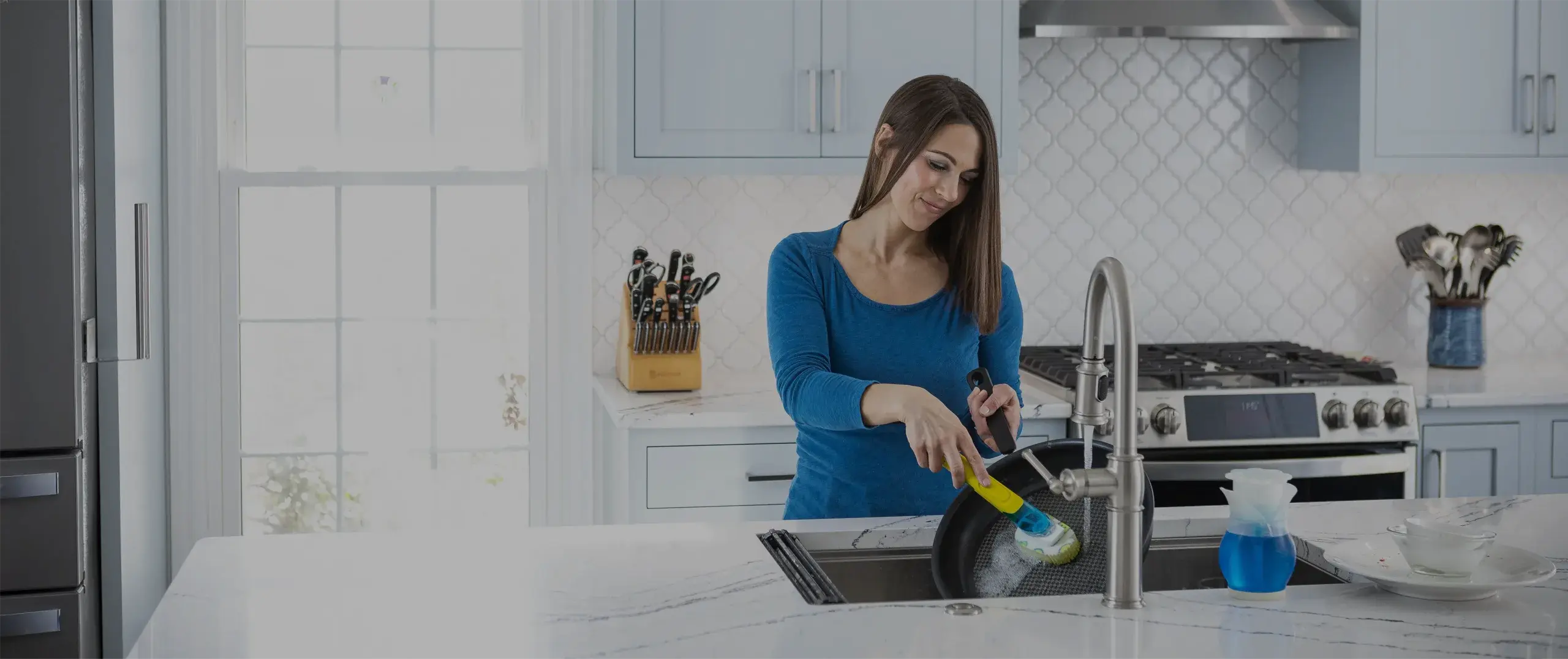 Woman smiling and using a scrubber in a kitchen